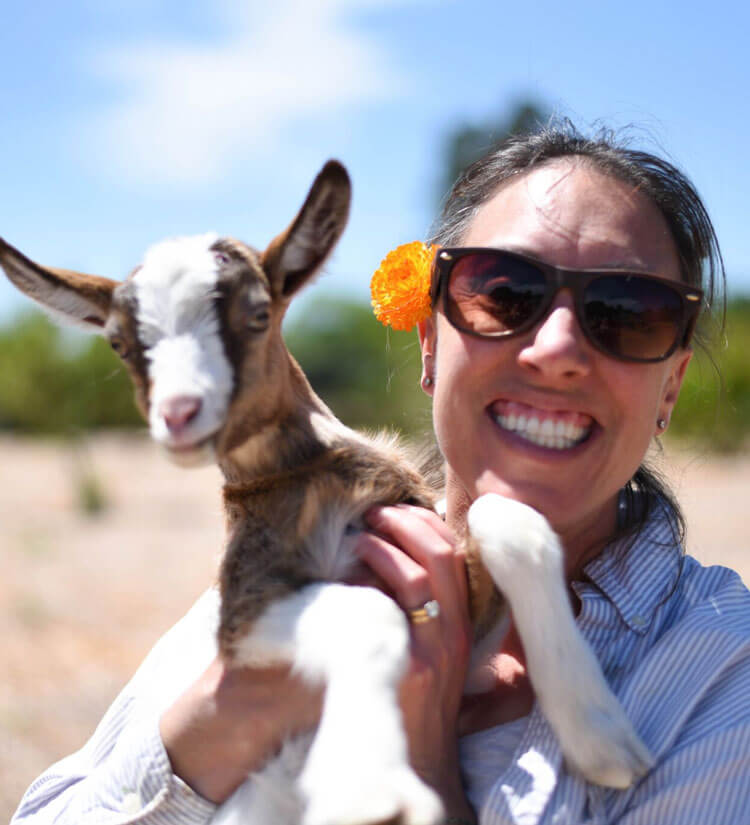 Happy woman holding a baby goat.